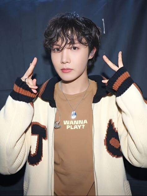 This contains an image of J-Hope making the peace sign with his hands